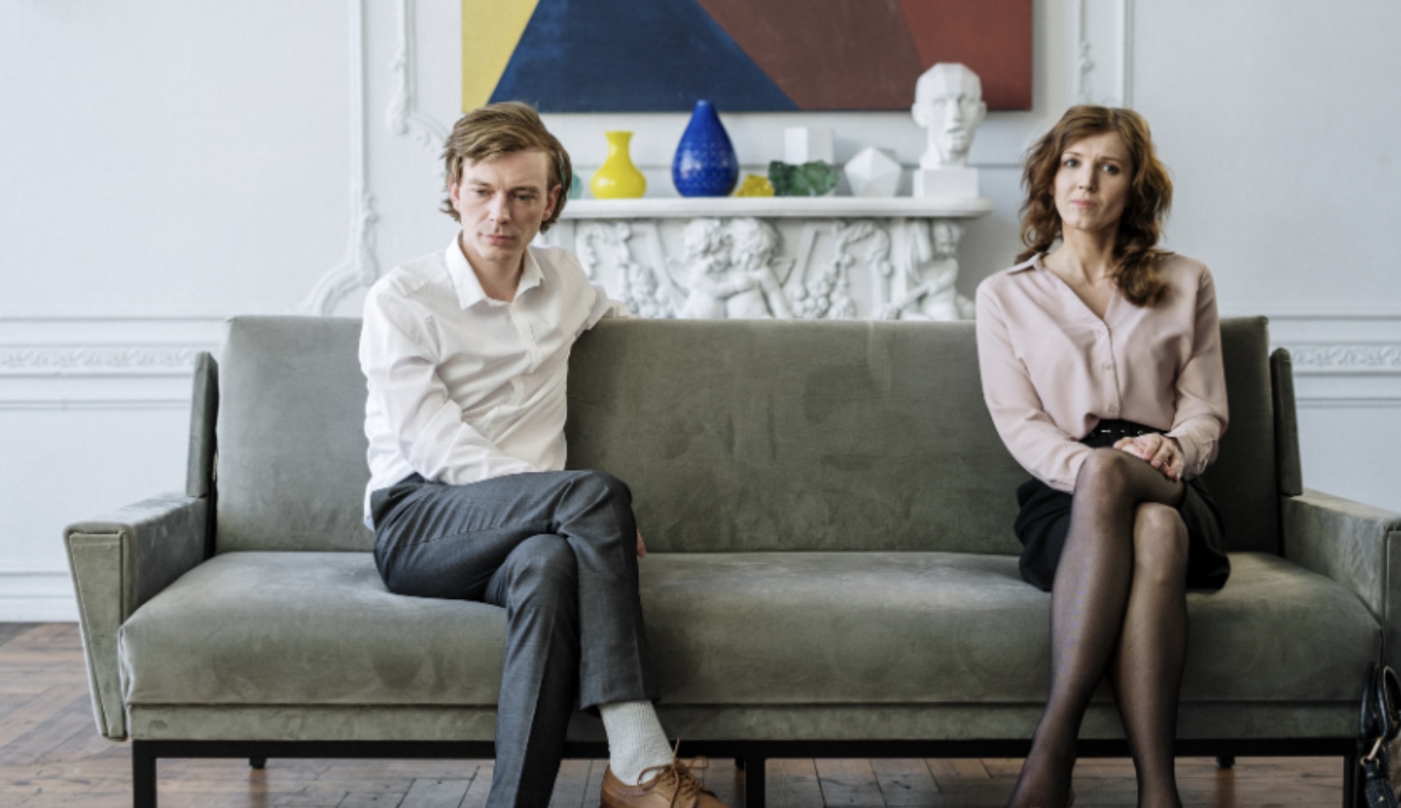 Unhappy couple sitting on a couch, possibly after an argument.