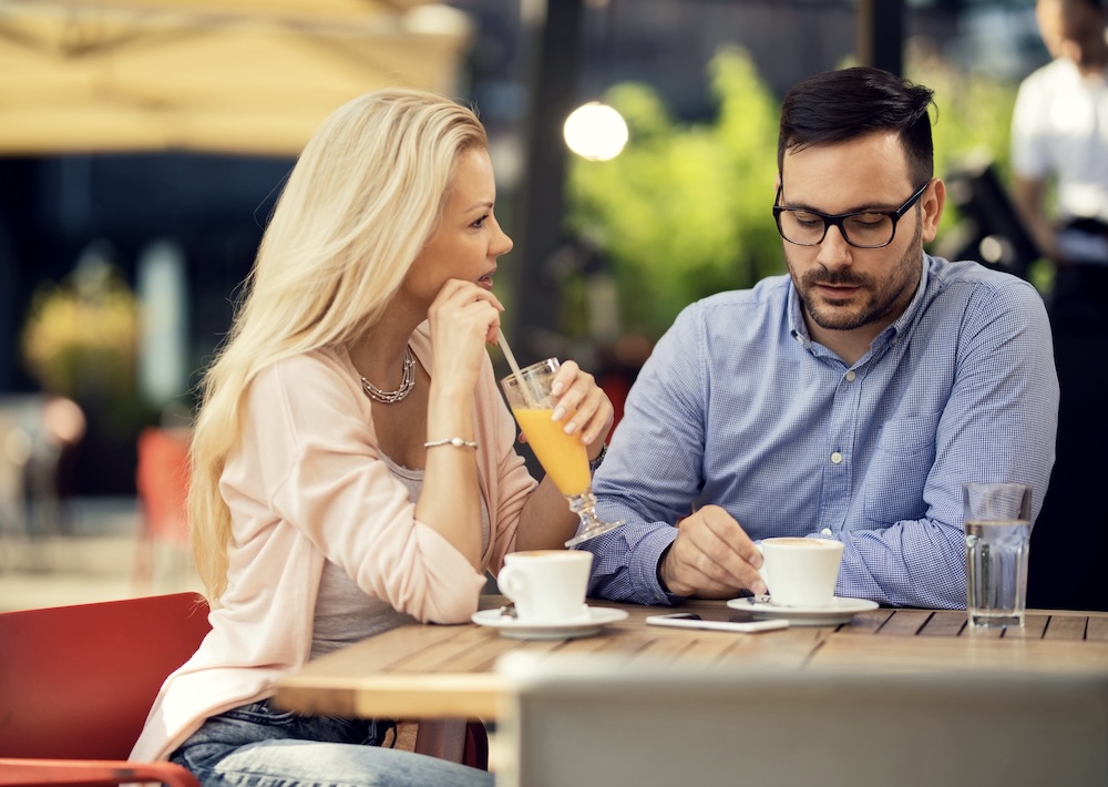 Couple discussing relationship struggles over coffee at an outdoor cafe.